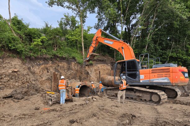 Construction workers and excavator at worksite.